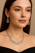 Model wearing Violet Vows silver CZ necklace and earrings set with circular spiral motifs.