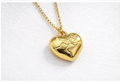 Close-up of a gold heart pendant necklace with sculpted heart detail by Violet Vows on a white surface