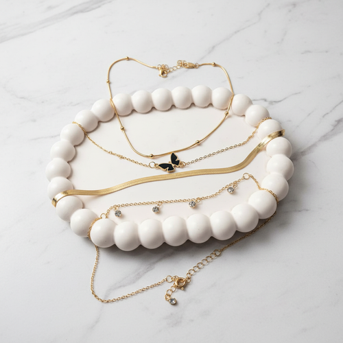 Set of gold and white beaded necklaces on a marble surface