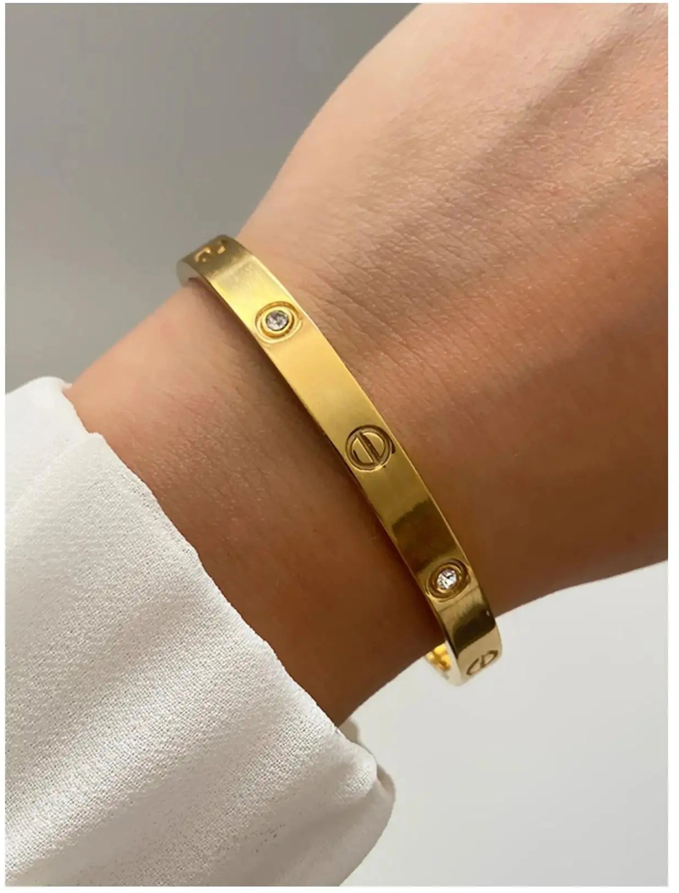 Gold bracelet with diamond accents on a wrist against a neutral background