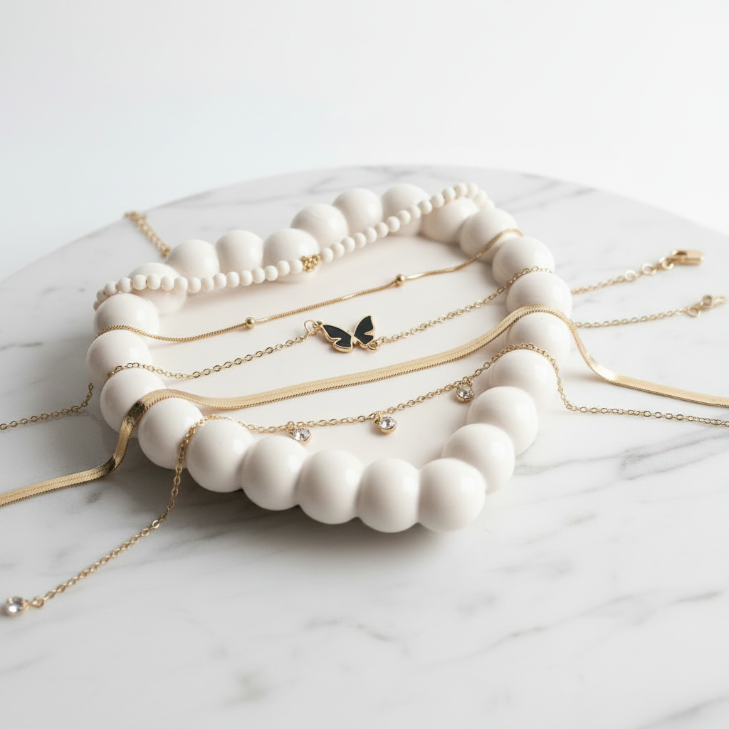 White beaded jewelry holder with gold necklaces on a marble surface