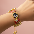 Bracelet watch with elephant charms on wrist against blush background