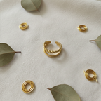 Gold double band twisted rope and plain open cuff ring on ivory linen with gold wire and eucalyptus