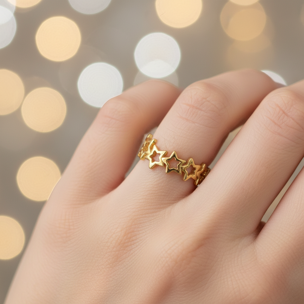 Gold linked star cutout band open cuff ring worn on finger with dreamy golden bokeh