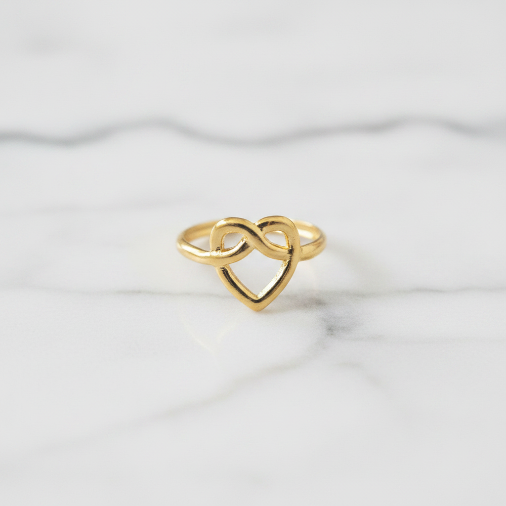 Gold infinity heart open cuff ring on white marble surface