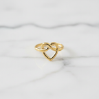 Gold infinity heart open cuff ring on white marble surface