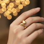 Gold teardrop dome bypass open cuff ring worn on finger with warm golden bokeh