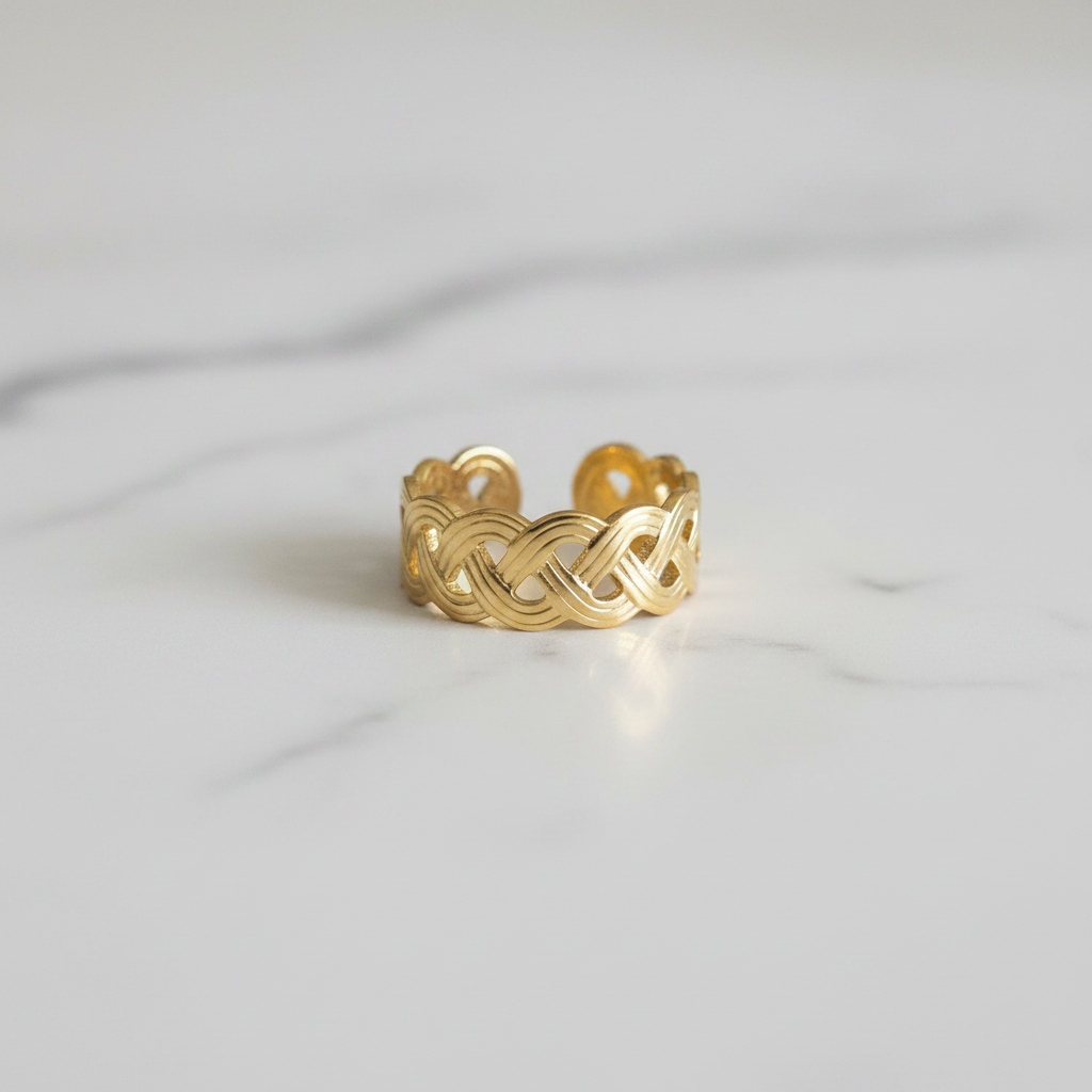 Gold infinity knot weave open cuff ring on white marble surface