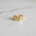 Gold infinity knot weave open cuff ring on white marble surface