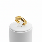 Gold molten wave sculptural open cuff ring on white jewelry stand, clean studio shot