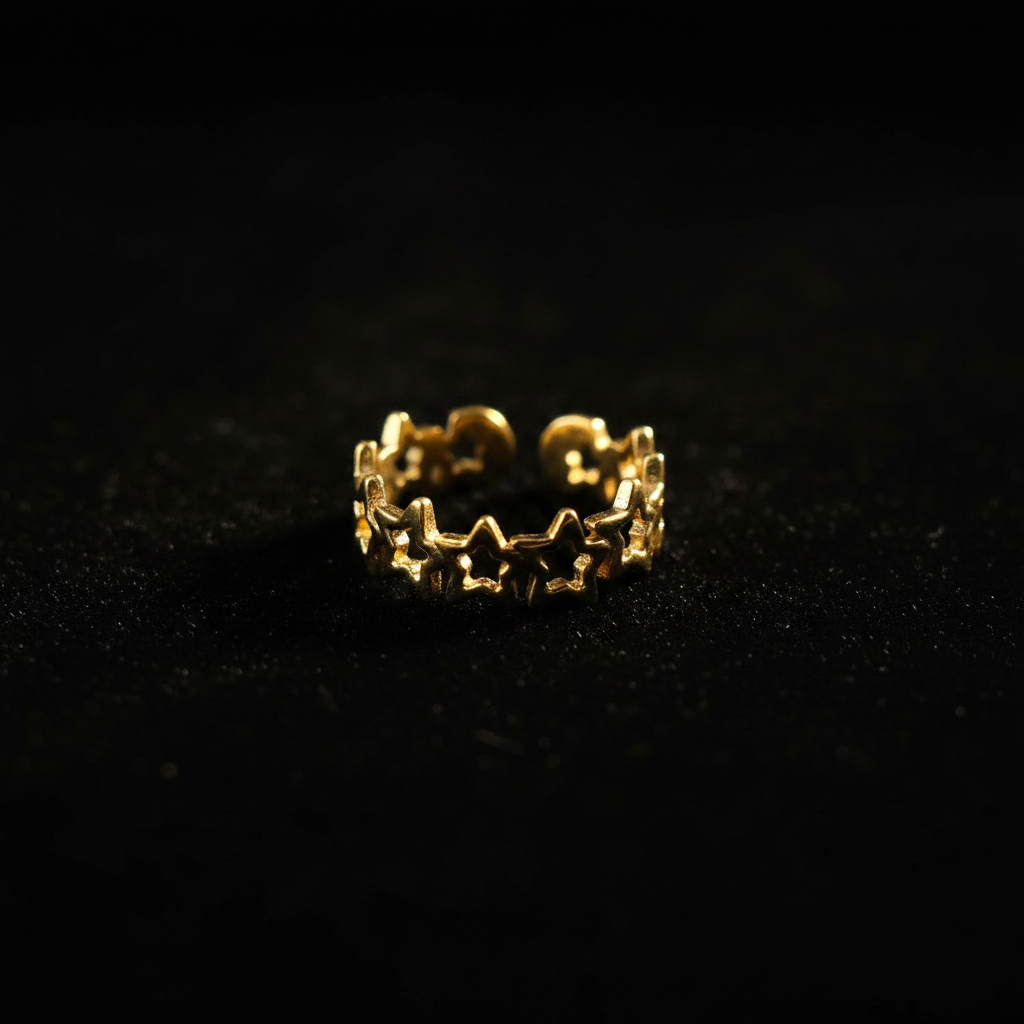 Gold linked star cutout band open cuff ring on black velvet with dramatic rim lighting