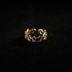 Gold linked star cutout band open cuff ring on black velvet with dramatic rim lighting