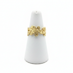 Gold flower bloom open cuff ring on white jewelry stand, clean studio shot