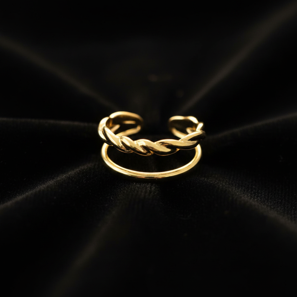 Gold double band twisted rope and plain open cuff ring on black velvet with dramatic rim lighting