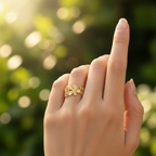 Gold flower bloom open cuff ring worn on finger with garden bokeh background