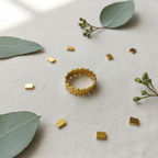 Gold vertical bar link wide band open cuff ring on ivory linen with gold rectangular pieces and eucalyptus