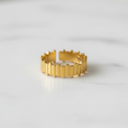 Gold vertical bar link wide band open cuff ring on white marble surface