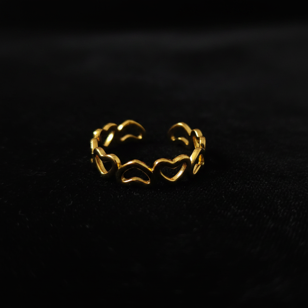Gold open heart cutout band open cuff ring on black velvet with dramatic rim lighting