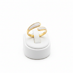 Gold and white stone bypass open cuff ring on white jewelry stand, clean studio shot