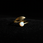 Gold leaf and white stone bypass open cuff ring on black velvet with dramatic rim lighting