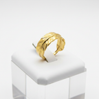 Gold feather engraved open cuff ring on white jewelry stand, clean studio shot