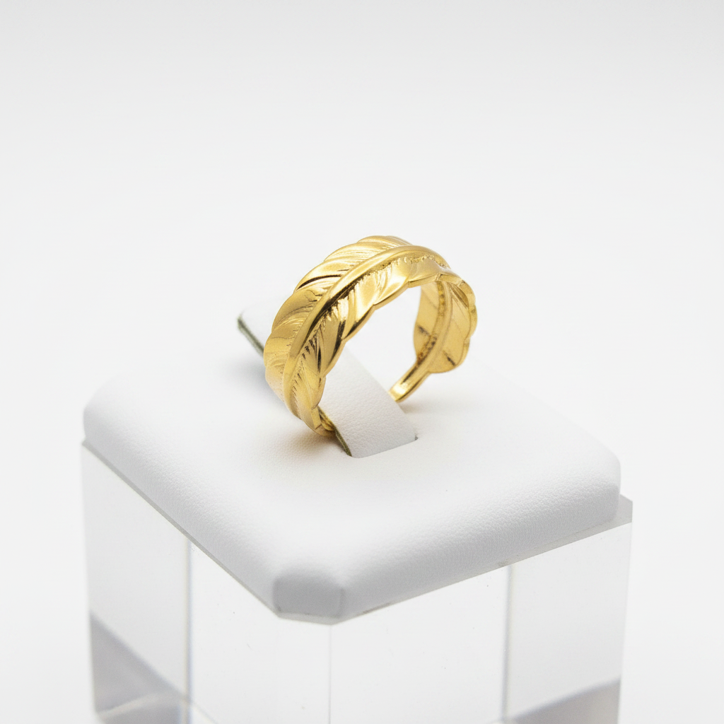 Gold feather engraved open cuff ring on white jewelry stand, clean studio shot