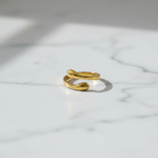 Gold hug open band ring on white marble surface