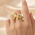 Gold Puffy 3D Bow Open Cuff Ring - worn on finger cream background lifestyle shot