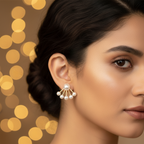 Model wearing multi-pearl fan ear jacket earrings - 5 graduating pearls in gold fan arc formation hugging the earlobe with warm bokeh lights background