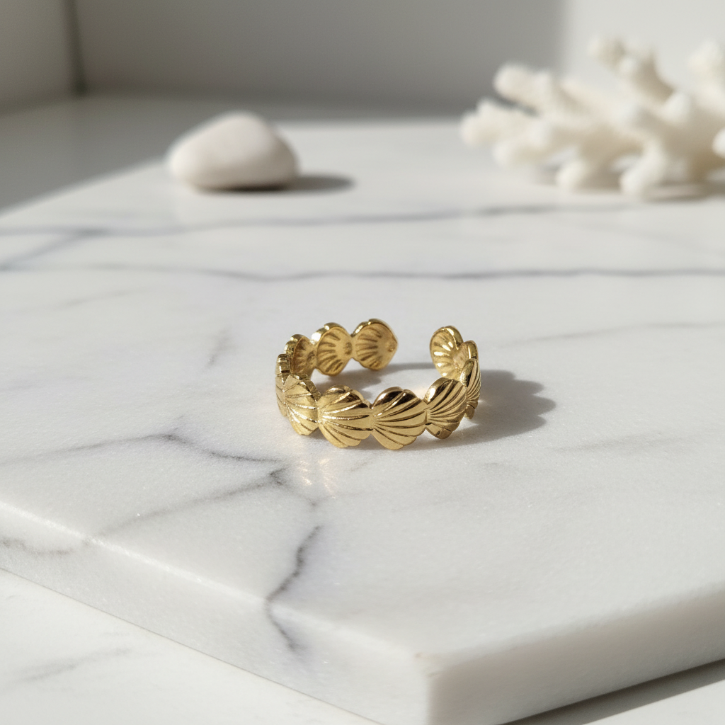 Gold seashell band open ring on white marble surface