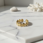 Gold seashell band open ring on white marble surface