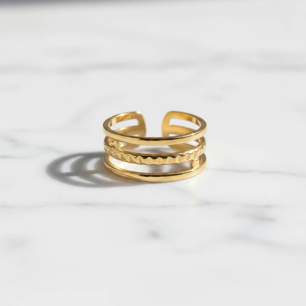 Gold triple layer open cuff ring on white marble surface