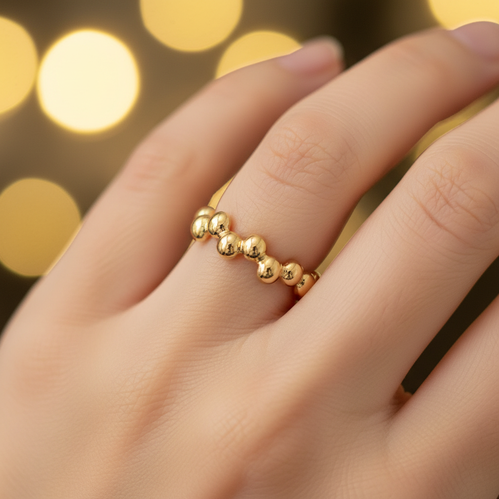 Gold beaded bubble band open cuff ring worn on finger with warm golden bokeh