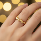 Gold beaded bubble band open cuff ring worn on finger with warm golden bokeh