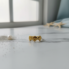 Gold triple seashell open band ring on white marble surface