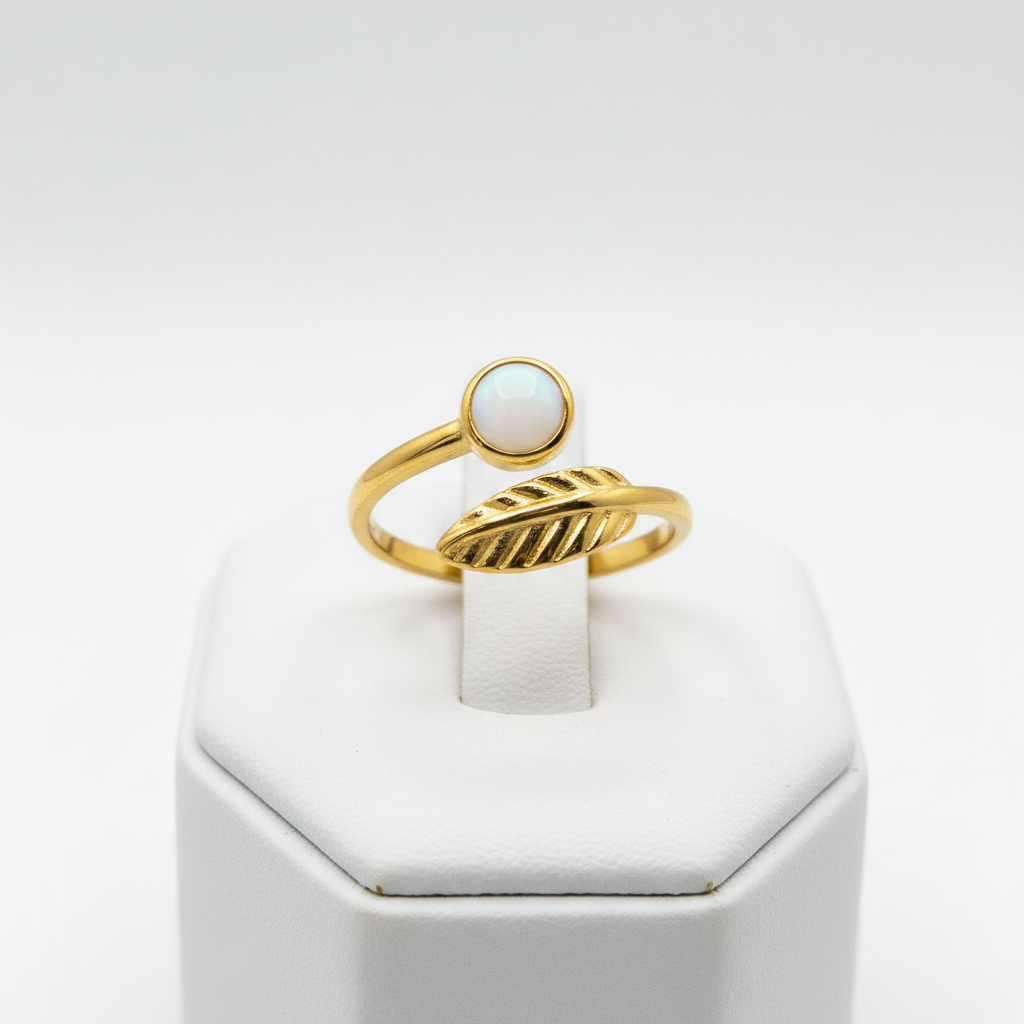 Gold leaf and white stone bypass open cuff ring on white jewelry stand, clean studio shot