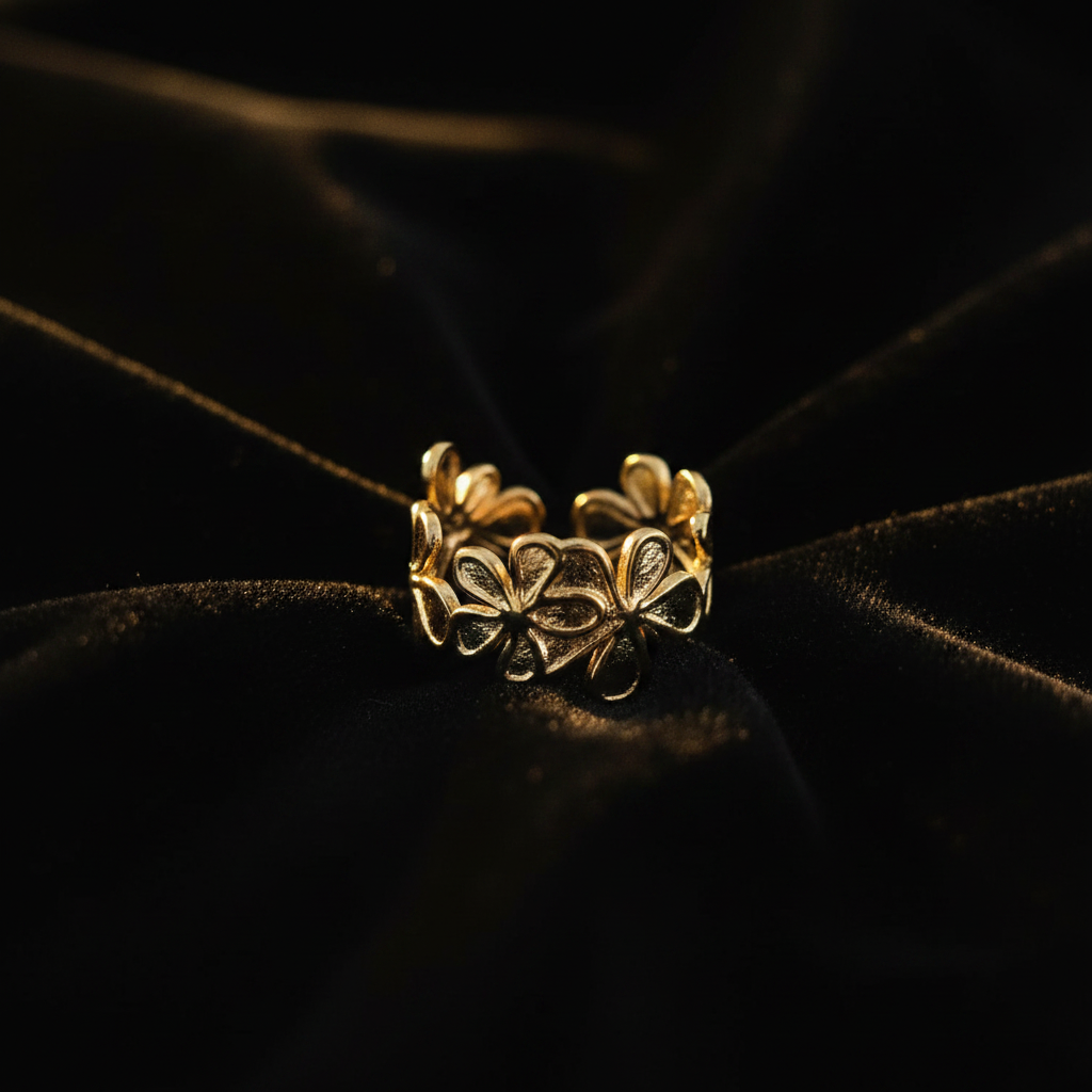 Gold flower bloom open cuff ring on black velvet with dramatic golden lighting