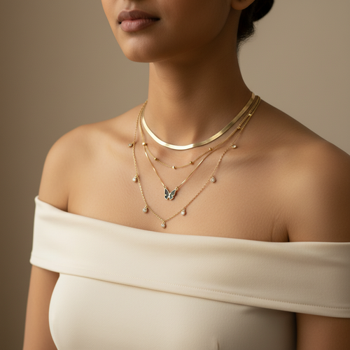 Model wearing 4-piece gold anti-tarnish necklace combo - layered herringbone, butterfly pendant, crystal charm, and satellite bead chains