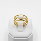Gold triple twisted rope band white oval stone open cuff ring on white jewelry stand, clean studio shot