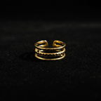 Gold triple layer open cuff ring on black velvet with dramatic rim lighting