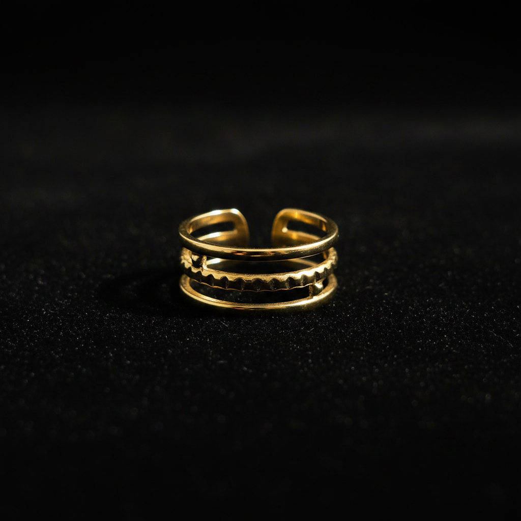 Gold triple layer open cuff ring on black velvet with dramatic rim lighting
