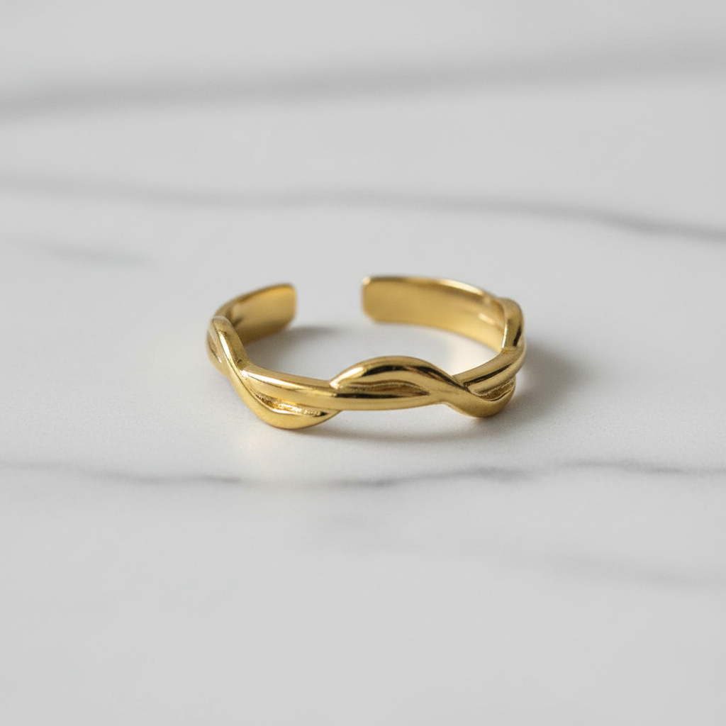 Gold twisted braided band open cuff ring on white marble surface