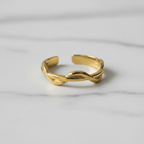 Gold twisted braided band open cuff ring on white marble surface