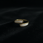 Gold and white stone bypass open cuff ring on black velvet with dramatic lighting