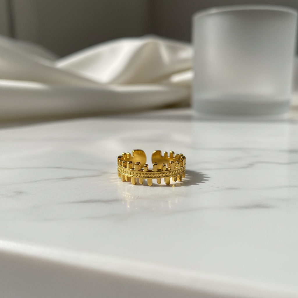 Gold crown battlements open band ring on white marble surface