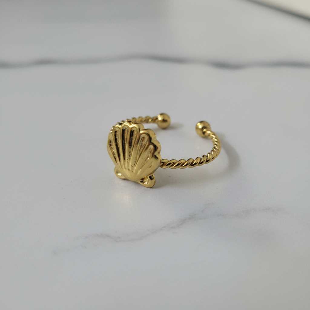 Gold seashell twisted rope open cuff ring on white marble surface