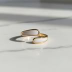 Gold and white stone bypass open cuff ring on white marble surface
