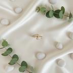 Gold and white stone bypass open cuff ring on ivory silk with white pebbles and eucalyptus
