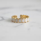 Gold white oval enamel wide band open cuff ring on white marble surface