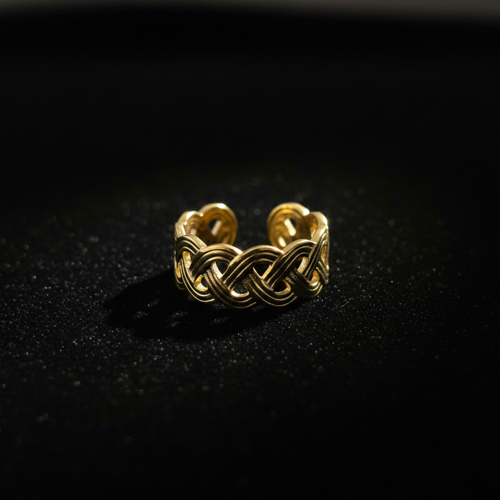 Gold infinity knot weave open cuff ring on black velvet with dramatic rim lighting